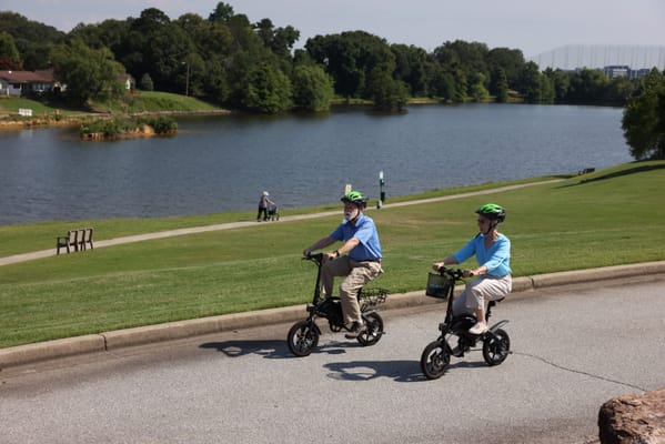 Residents riding scooters along a lakeside path