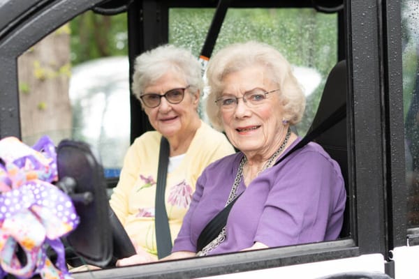 Two elderly women smiling in a vehicle