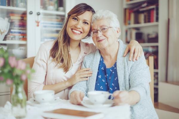 A caregiver and resident smiling together in a cozy room