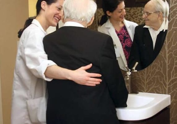 Staff assisting resident at a sink in the facility