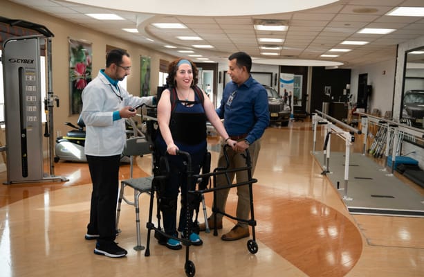 Therapist assisting resident with a walker in a gym
