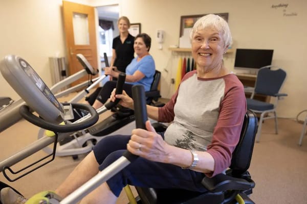 Residents exercising in a fitness room with equipment
