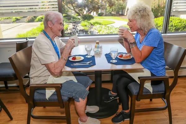 Two residents enjoying tea with dessert in a dining area