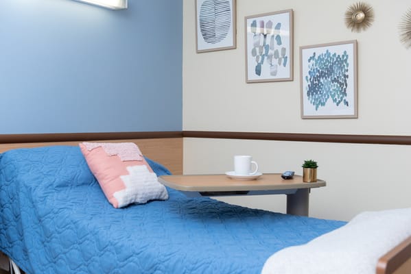 A cozy resident room with blue bedding and wall art