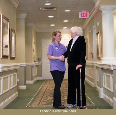 Staff member assisting a resident in a hallway