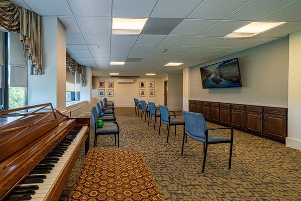 Bright activity room with chairs and a piano