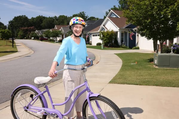 Senior woman riding a purple bicycle on a sunny street