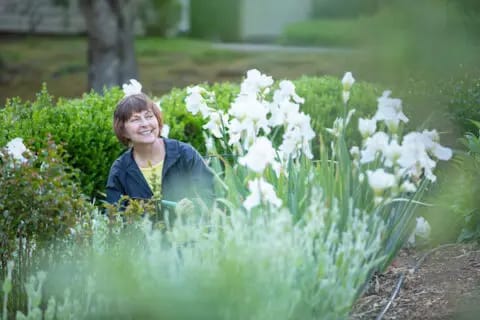 A resident smiling in a flower garden
