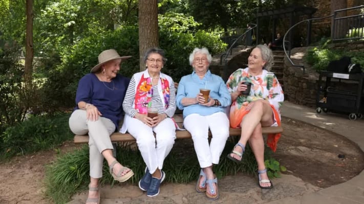 Four seniors enjoying drinks in a garden setting
