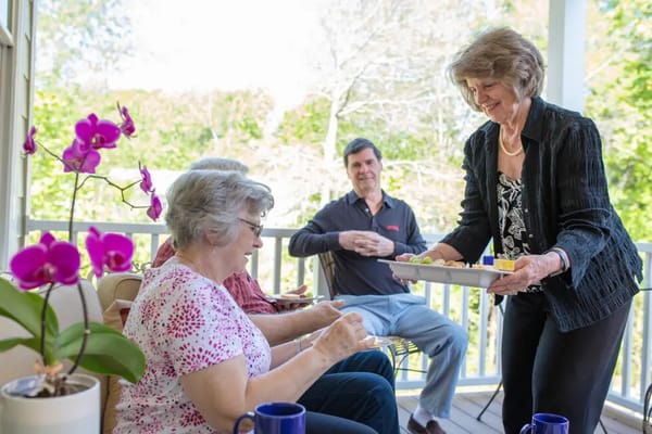 Residents enjoying snacks outdoors with staff assistance