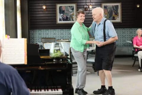 A couple dancing in a common area with piano music