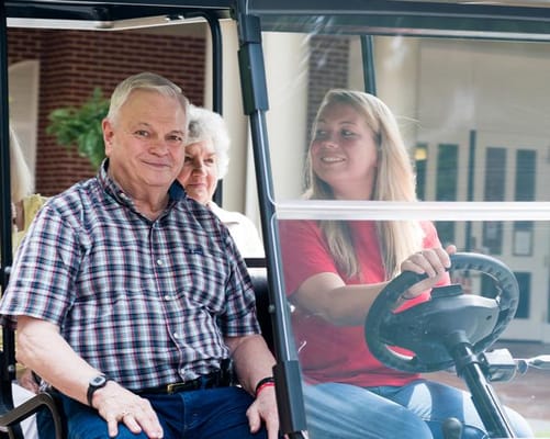 Residents and staff smiling in a facility vehicle