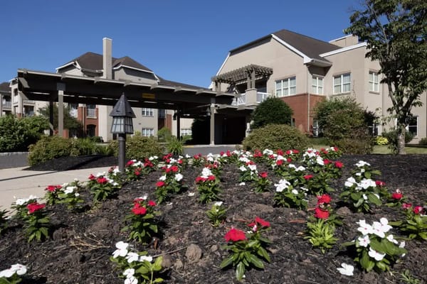 Exterior view of a senior living facility with flower beds