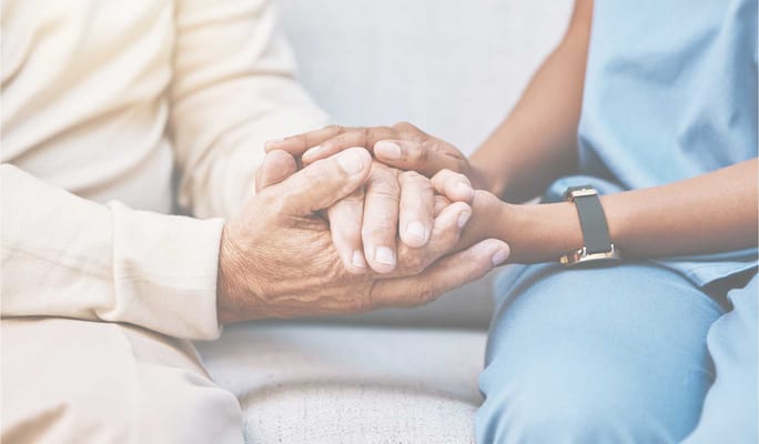 Close-up of a caregiver holding a senior's hands