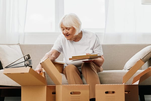 Senior woman unpacking boxes in a cozy living room
