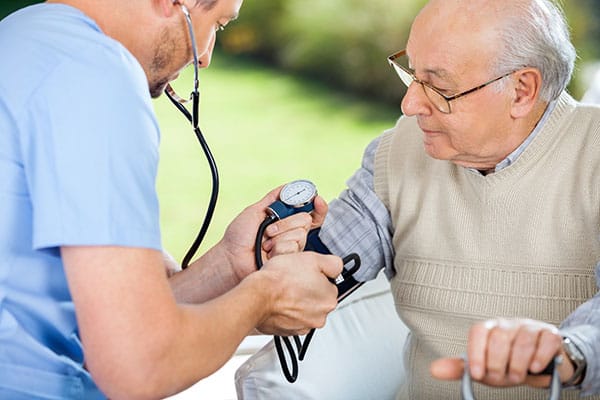 Nurse checking blood pressure of an elderly man outdoors
