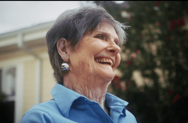 Senior woman smiling outdoors in bright clothing