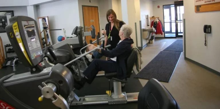 Resident exercising with staff support in an activity room