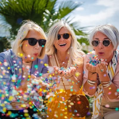 Three women celebrating with colorful confetti outdoors