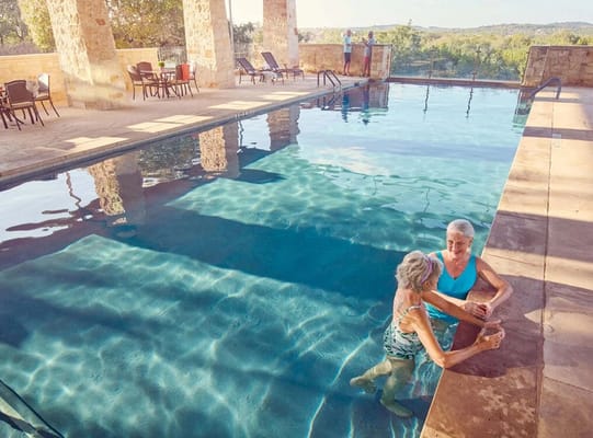 Two senior women relaxing by a swimming pool