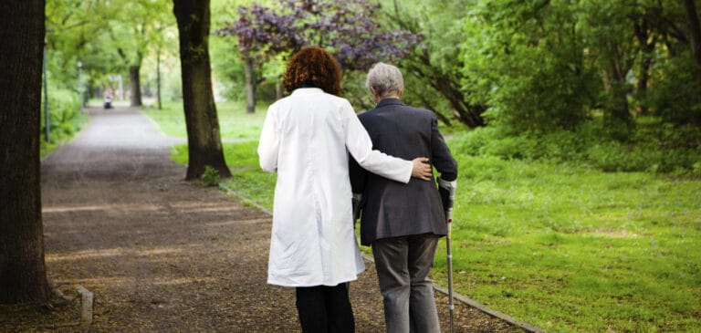 A caregiver assisting a senior in a park