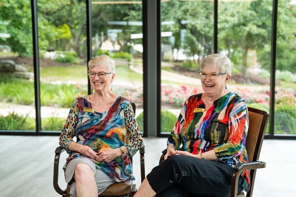 Two smiling residents sitting indoors