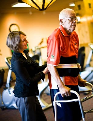 Staff assisting a resident in a gym setting