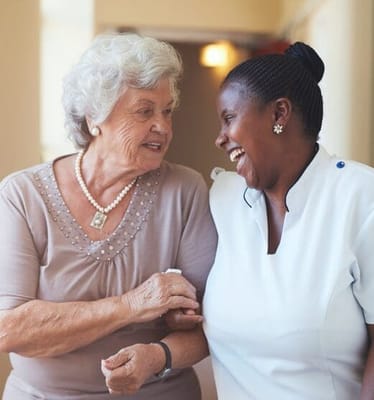 A resident and staff member smiling together in a hallway