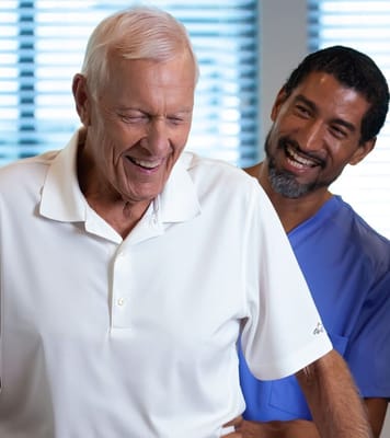 A senior resident laughing with a caregiver