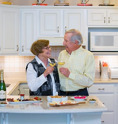 A couple toasting with drinks in a cozy kitchen
