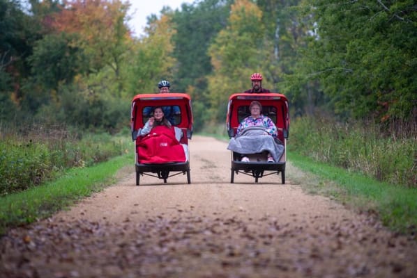 Residents enjoying a ride in cycle chairs on a path
