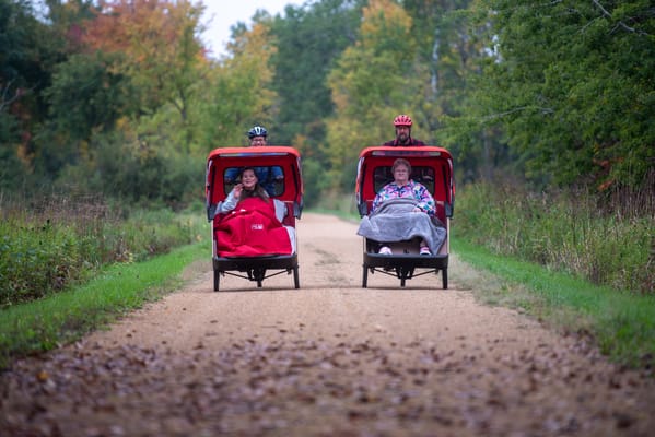 Residents enjoying a ride in cycle chairs on a path
