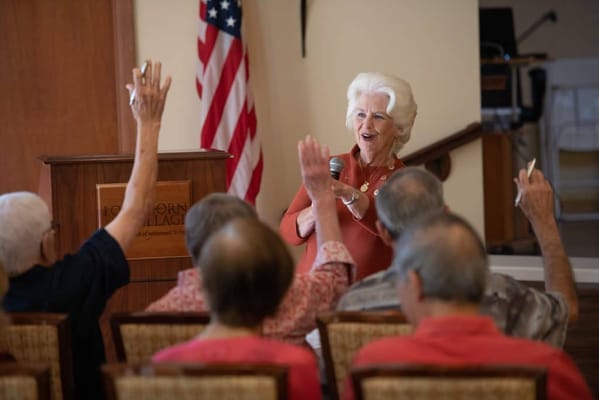 Residents engaging in an activity session with a woman speaking