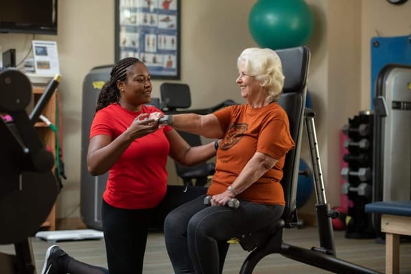 Resident exercising with a staff member in a fitness area
