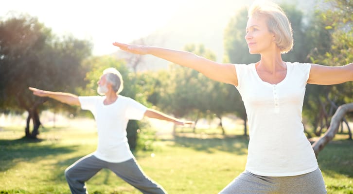 Seniors practicing yoga in a sunny outdoor space