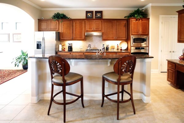 A kitchen area with wooden cabinets and barstools