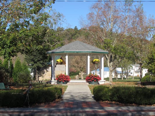 A gazebo surrounded by colorful flowers in a park