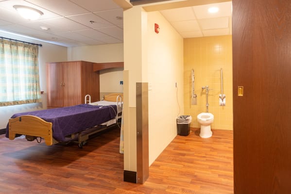 A well-lit private resident room with a bed and bathroom
