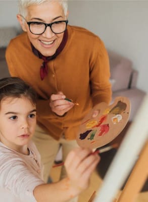 Senior woman and young girl painting together