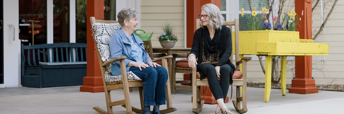 Residents chatting in rocking chairs outside a facility