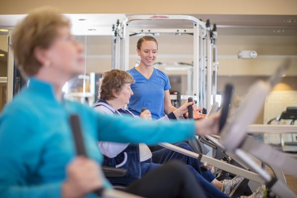 Residents exercising with staff supervision in a fitness area