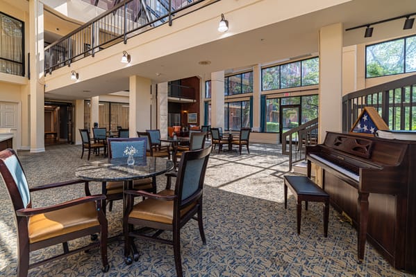 Sunlit common area with seating and a piano
