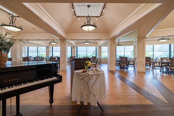 Bright dining area with a piano and floral centerpiece