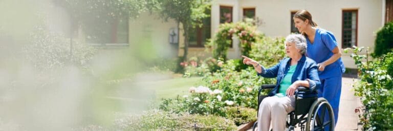 Resident enjoying a garden stroll with staff assistance