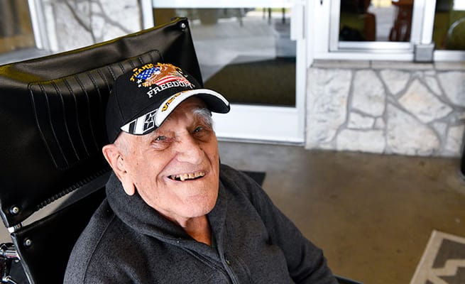 Smiling senior man in a wheelchair at an entrance