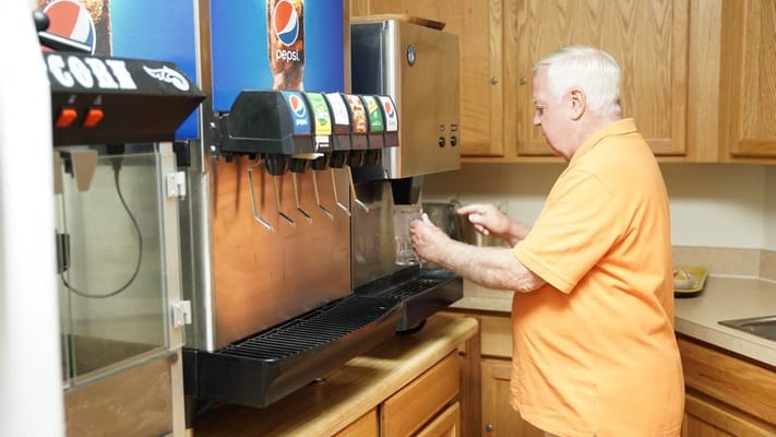 Resident using a beverage dispenser in the dining area