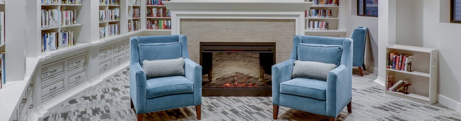 Cozy reading area with blue chairs and a fireplace