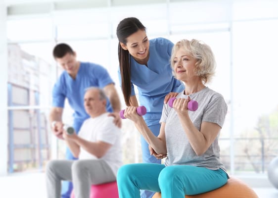 Elderly woman lifting weights with staff assistance