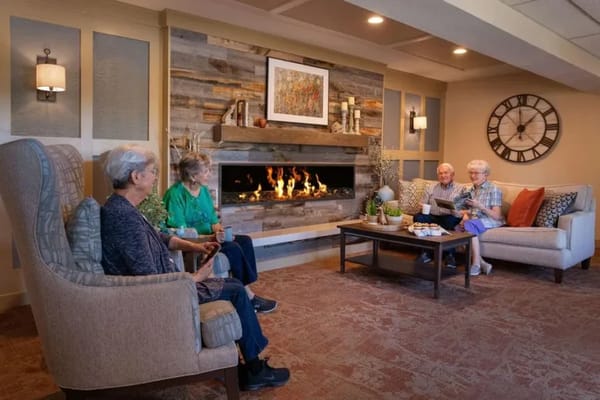 Residents enjoying a cozy common area by the fireplace