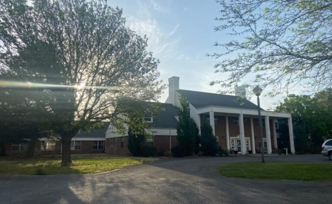 Exterior view of assisted living facility with trees and pathway